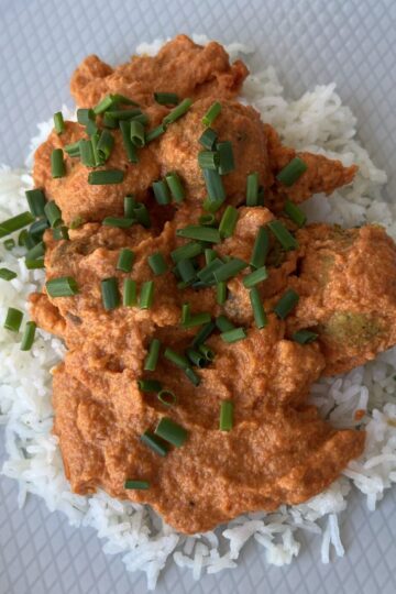 tempeh meatballs in roasted peppers sauce - on plate with rice