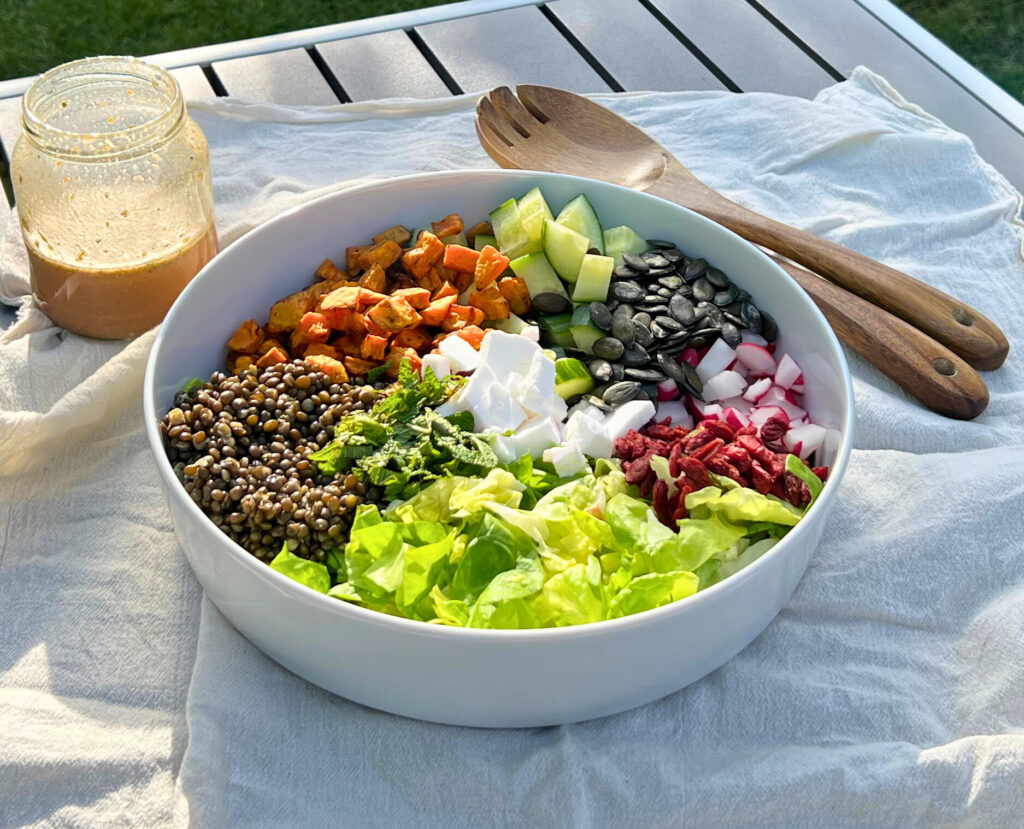 Black lentils and sweet potato salad big and colorful bowl, dressing and wooden spoons