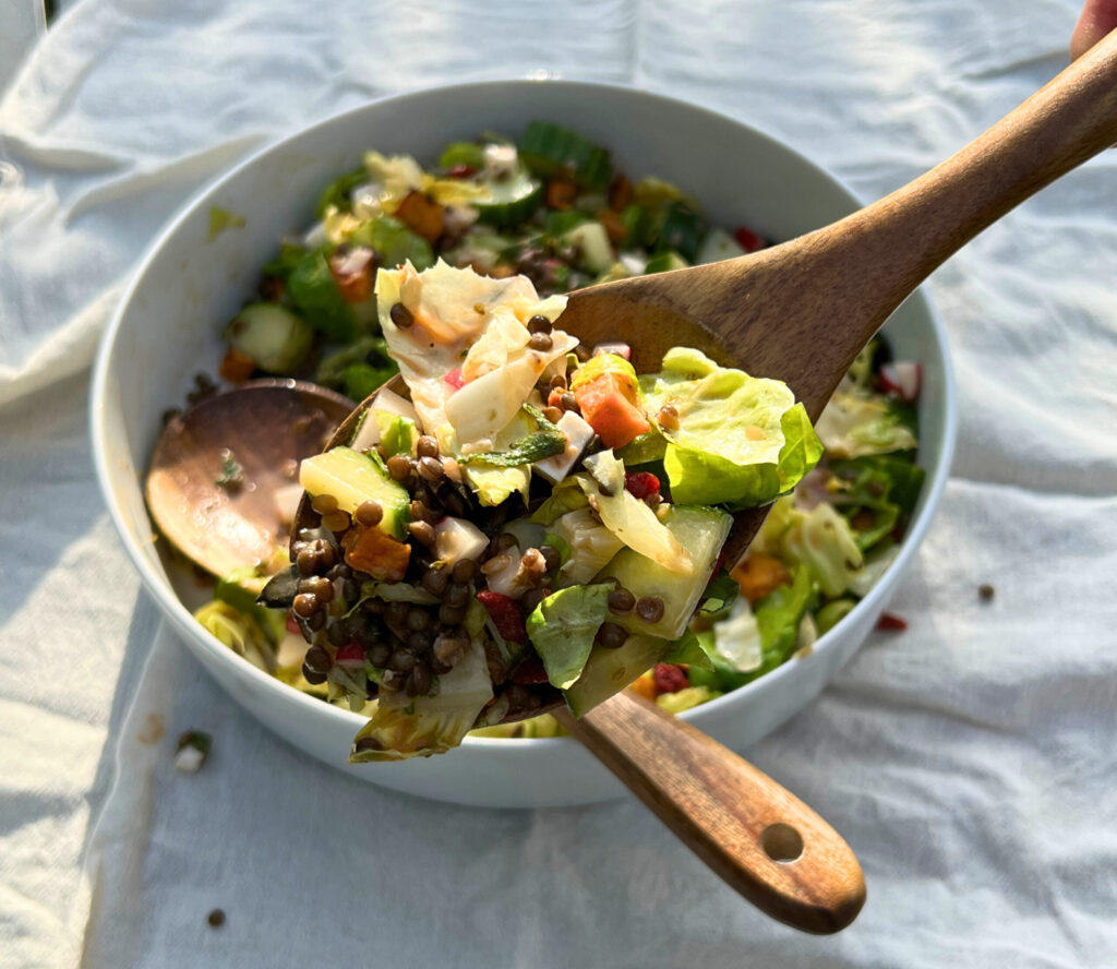 wooden spoon with colorful salat + dressing