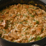 a wide pot with gf rice noodles with mushroom sauce, herbs, creamy