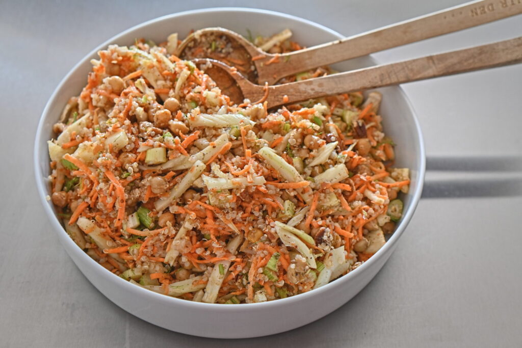 a serving bowl with carrot and fennel salad and serving spoon on a metal island