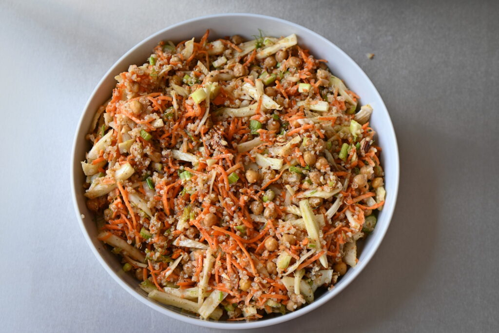 a serving bowl with carrot and fennel salad, with chickpeas and quinoa on a metal island