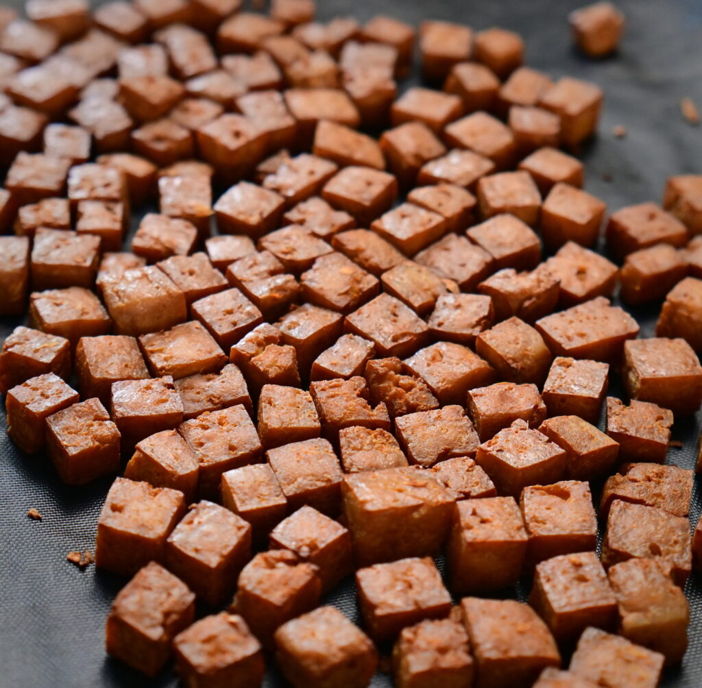 smoked tofu cubes spread on a black surface