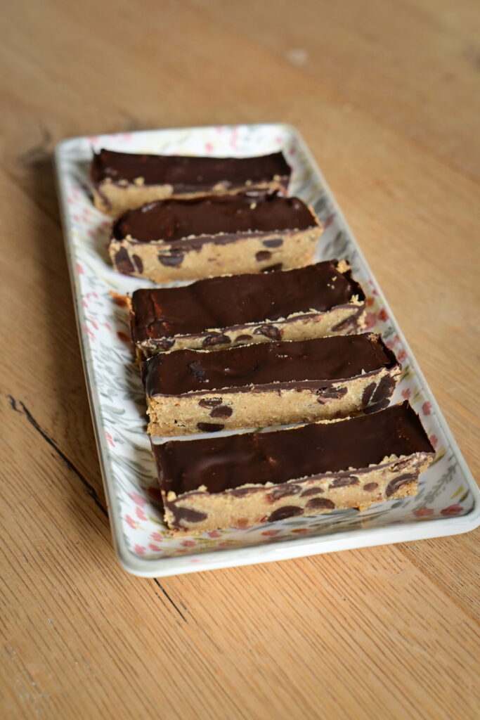 chickpea Protein Cookie Dough bars covered with chocolate on a flowered plate on a wooden surface