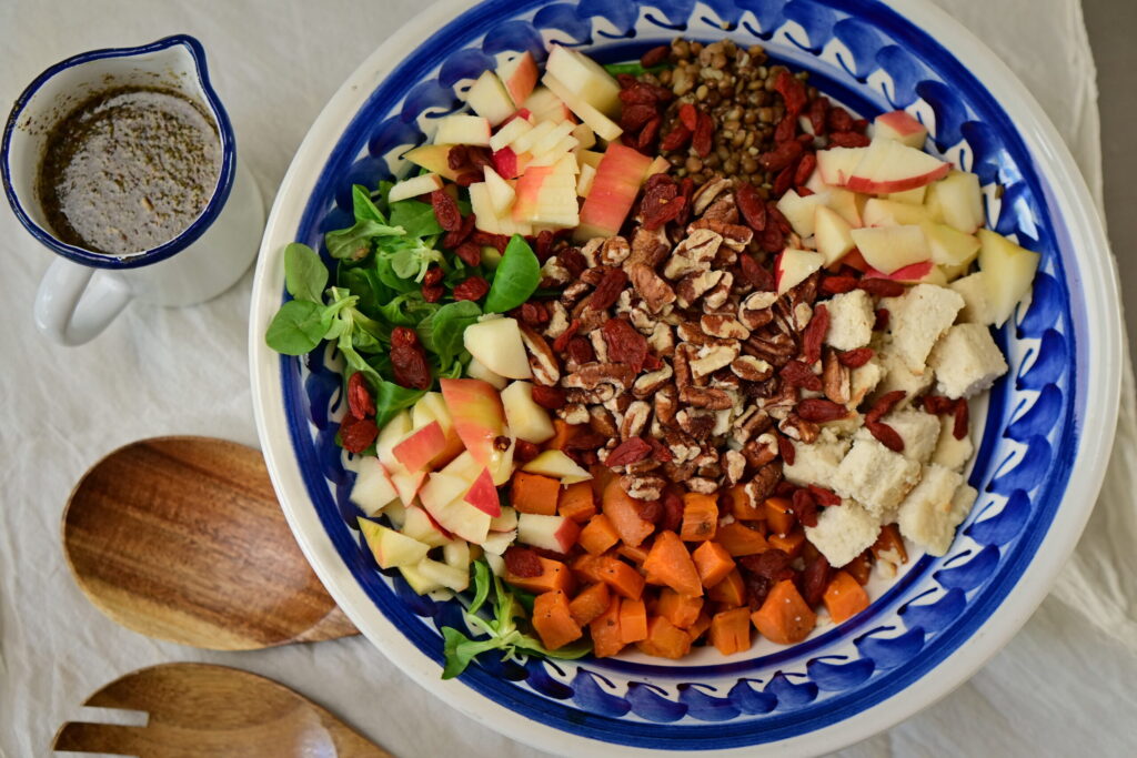 brown lentils and sweet potato salad with wooden spoons and blue bowl