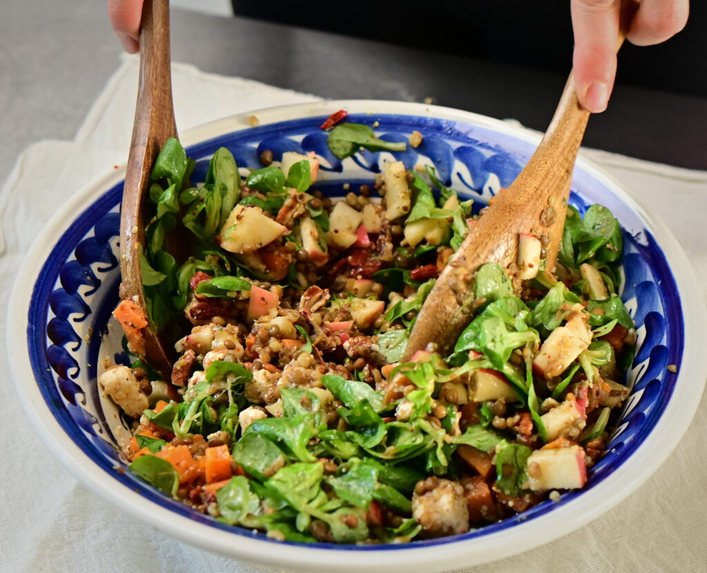 brown lentils and sweet potato salad with wooden spoons and blue bowl