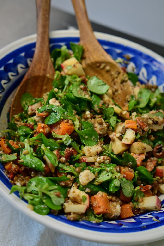 brown lentils and sweet potato salad with wooden spoons and blue bowl