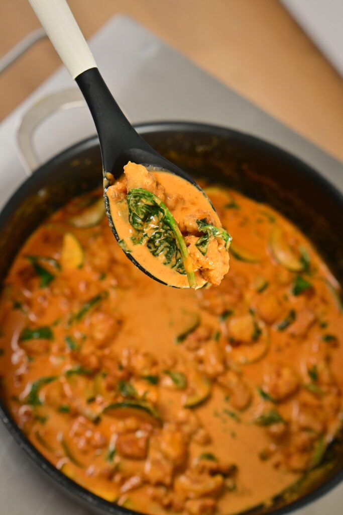 a pot with coconut lime tofu with herbs with a serving spoon