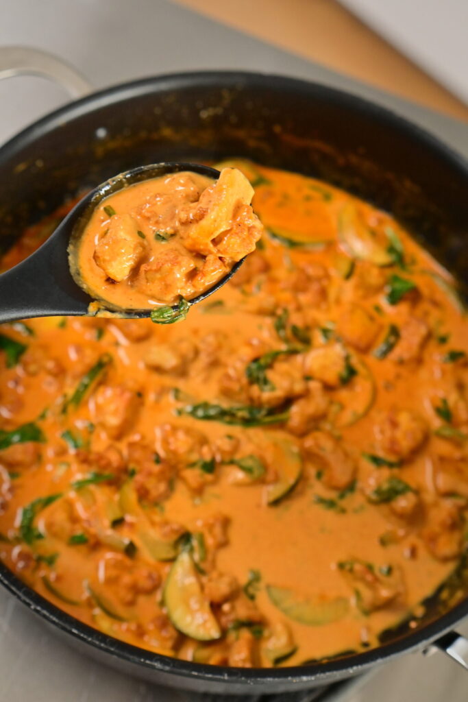 a pot with coconut lime tofu with herbs with a serving spoon