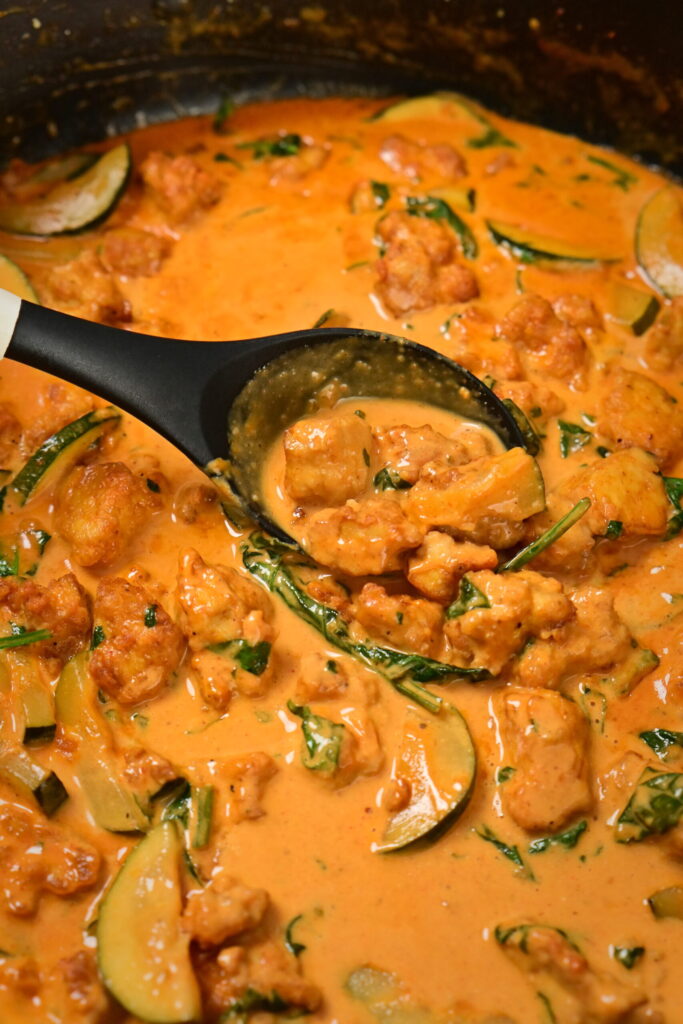 a pot with coconut lime tofu with herbs with a serving spoon