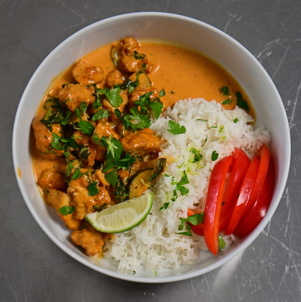 a bowl with coconut lime tofu with herbs, with basmati rice and red bell peppers, topped with herbs and lime zest