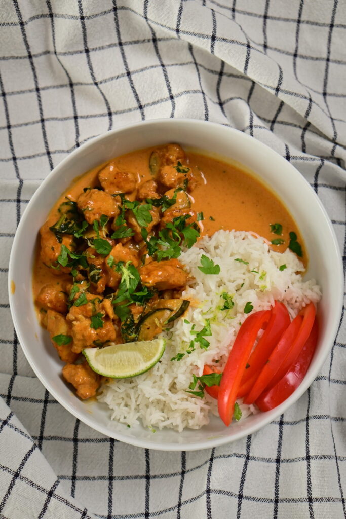 a bowl with coconut lime tofu with herbs, with basmati rice and red bell peppers, topped with herbs and lime zest