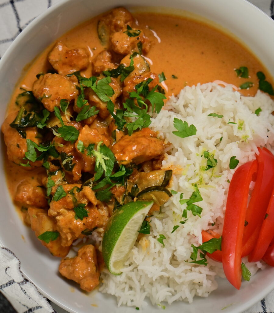 a bowl with coconut lime tofu with herbs, with basmati rice and red bell peppers, topped with herbs and lime zest
