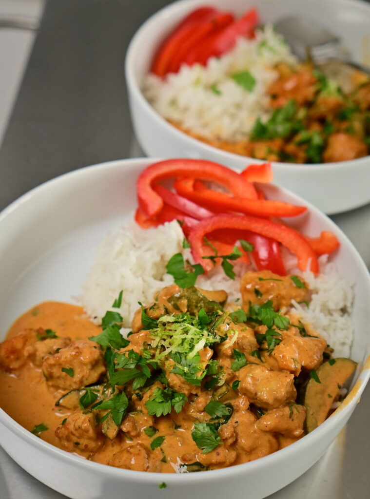 to bowls with coconut lime tofu with basmati rice and red bell peppers, topped with herbs and lime zest