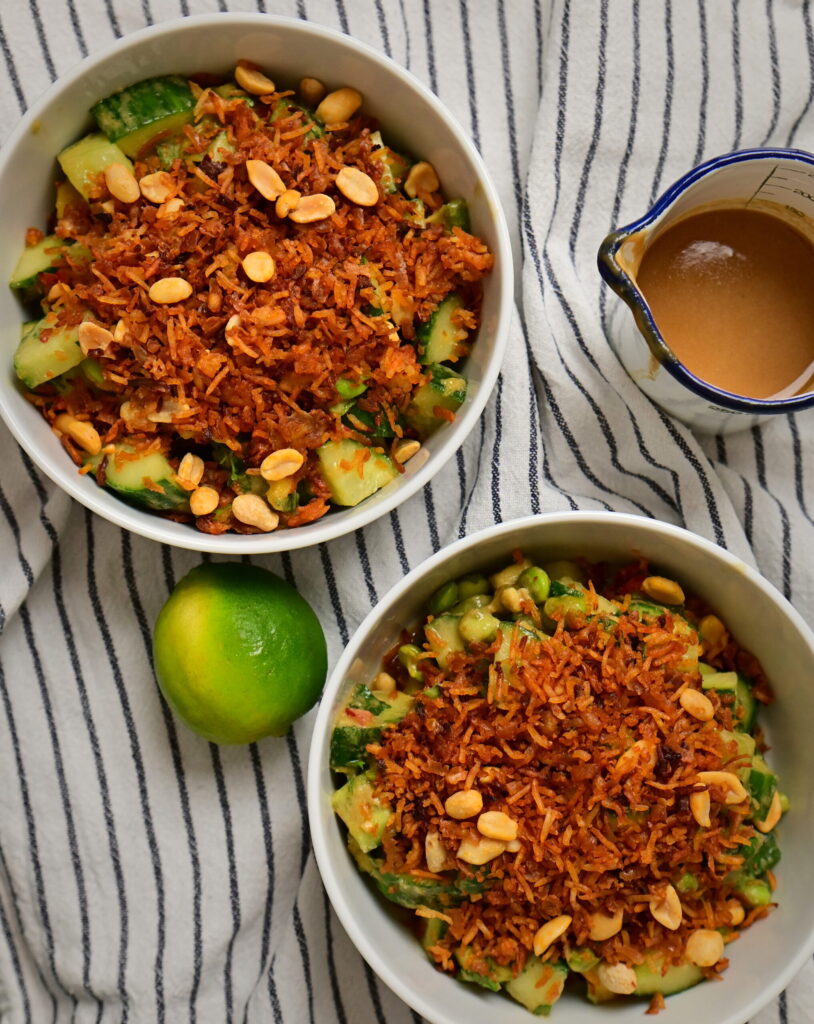 Two bowls of Thai-style crispy rice salad with lime and peanut sauce on a striped tablecloth