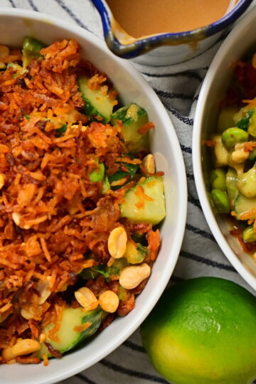 Two bowls of Thai-style crispy rice salad with lime and peanut sauce on a striped tablecloth