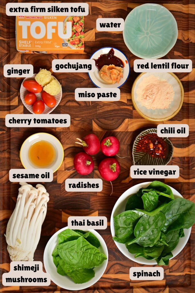 vegan mapo tofu ingredients arranged on a checkered wooden cutting board.