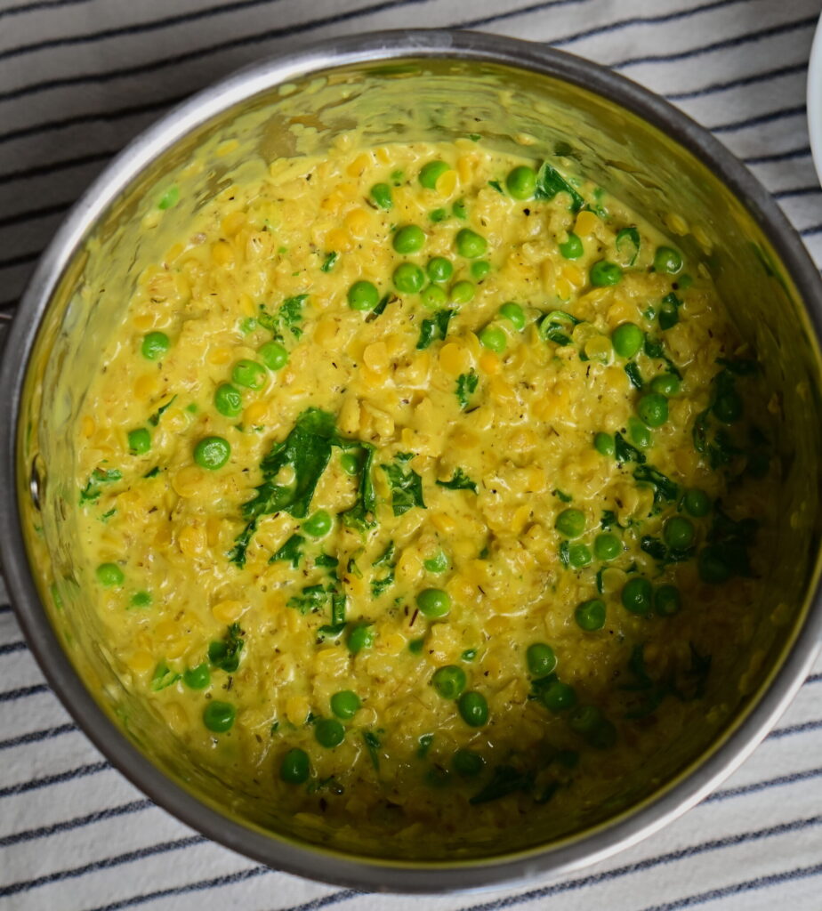 A pot with Savory ״Cheesy" Oatmeal placed on a white cloth with blue stripes