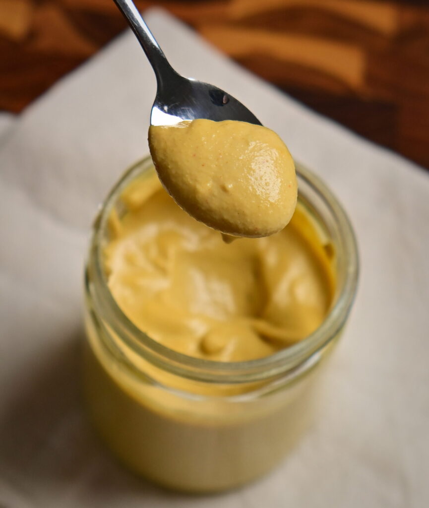 vegan yellow cheese sauce in a jar with a spoon