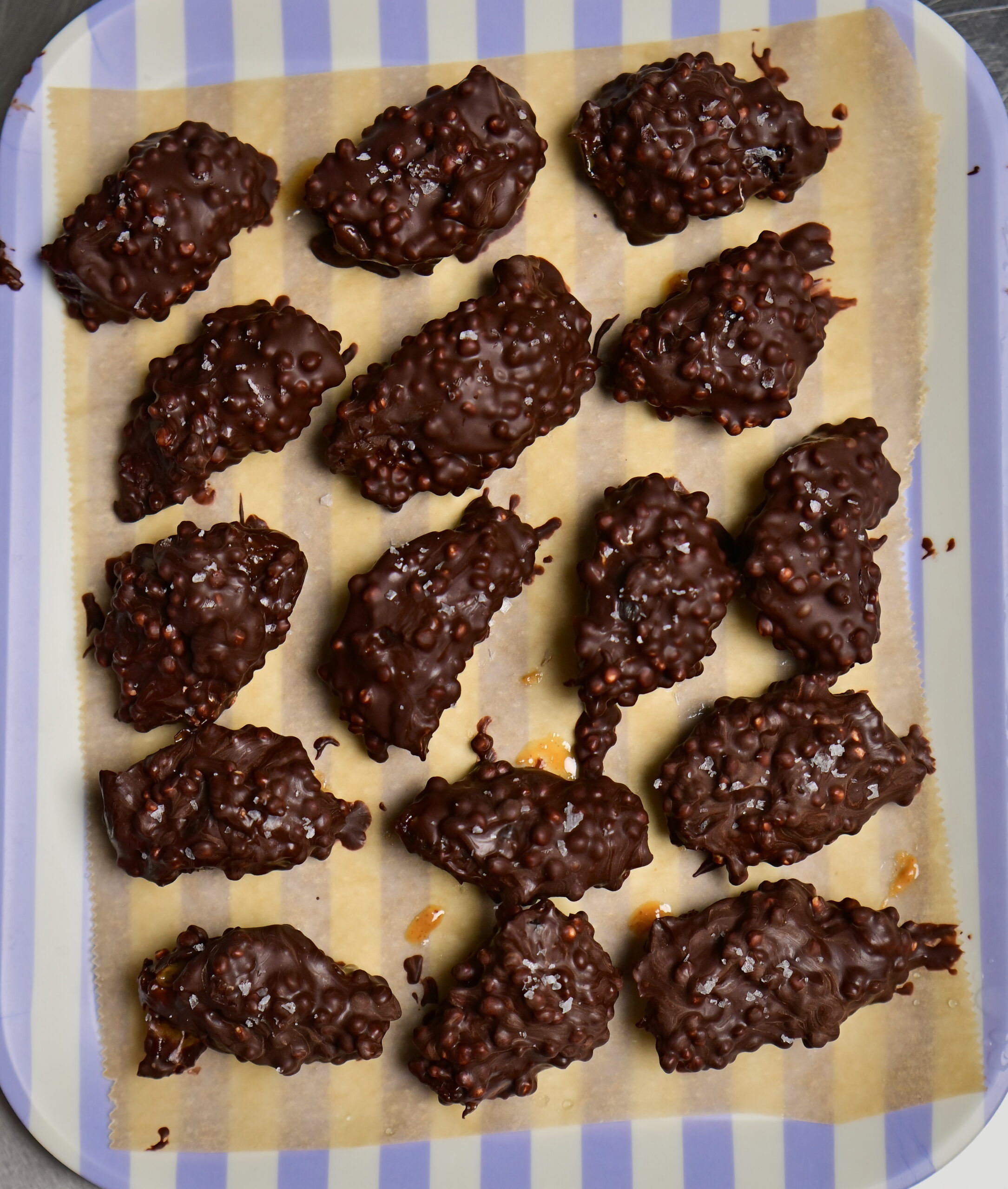 stuffed dates covered in chocolate + puffed quinoa over paper