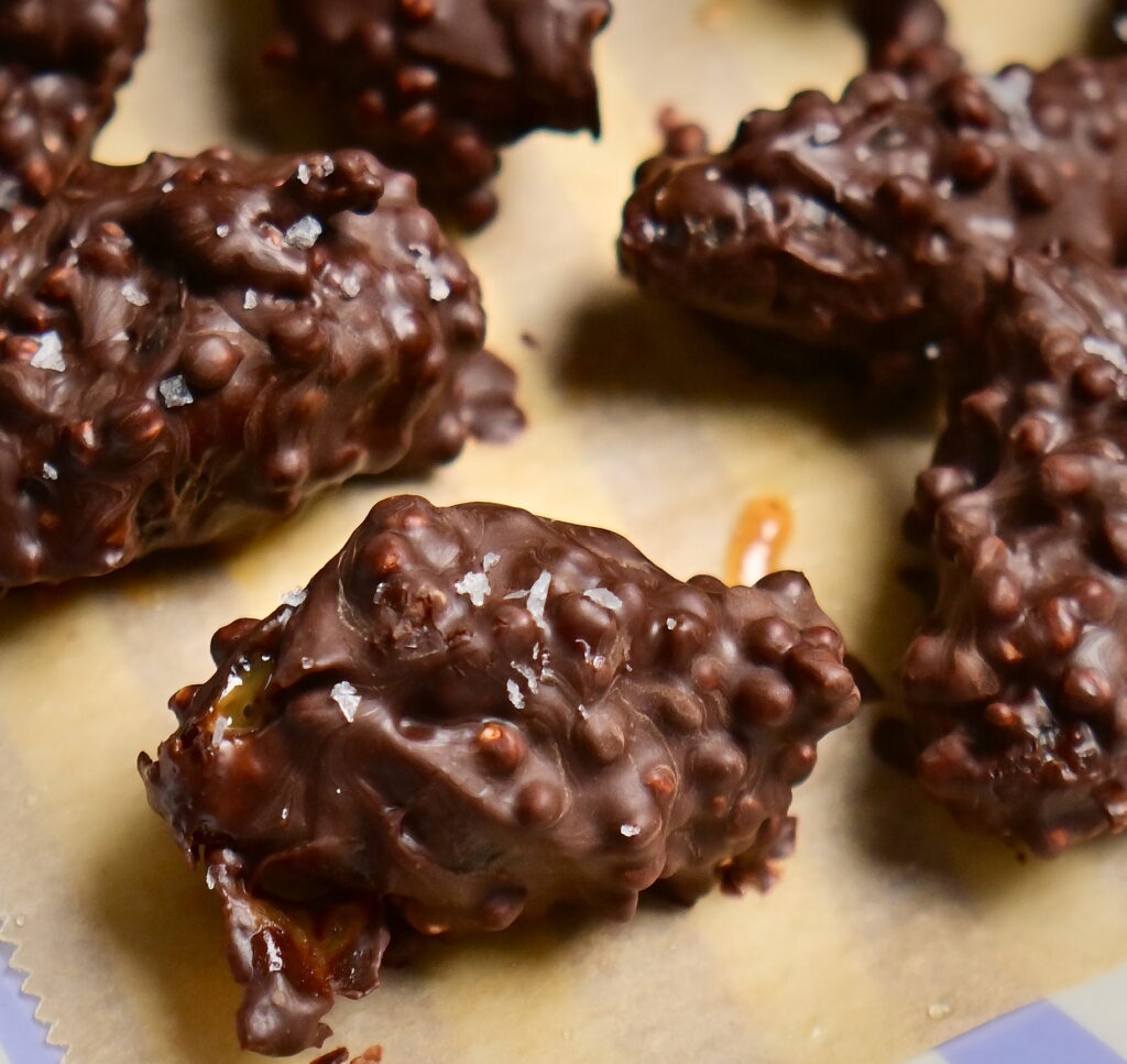 stuffed date covered in chocolate + puffed quinoa over paper
