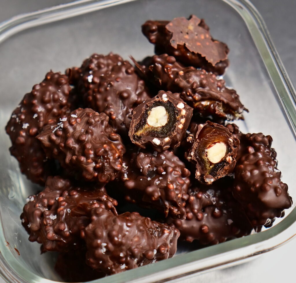 fancy stuffed dates covered in chocolate in a glass container