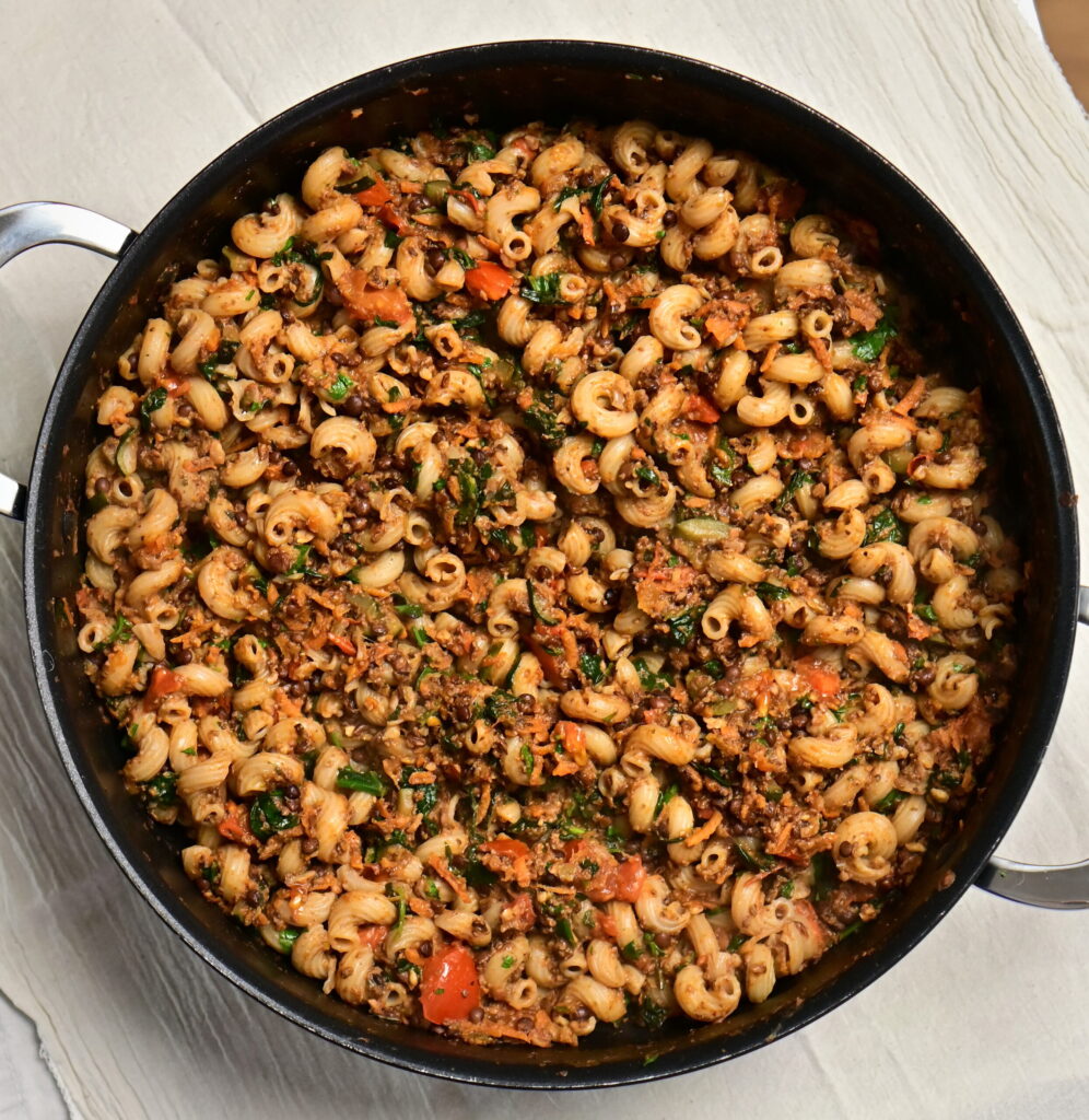 A pot of lentil and mushroom ragù with curly pasta.