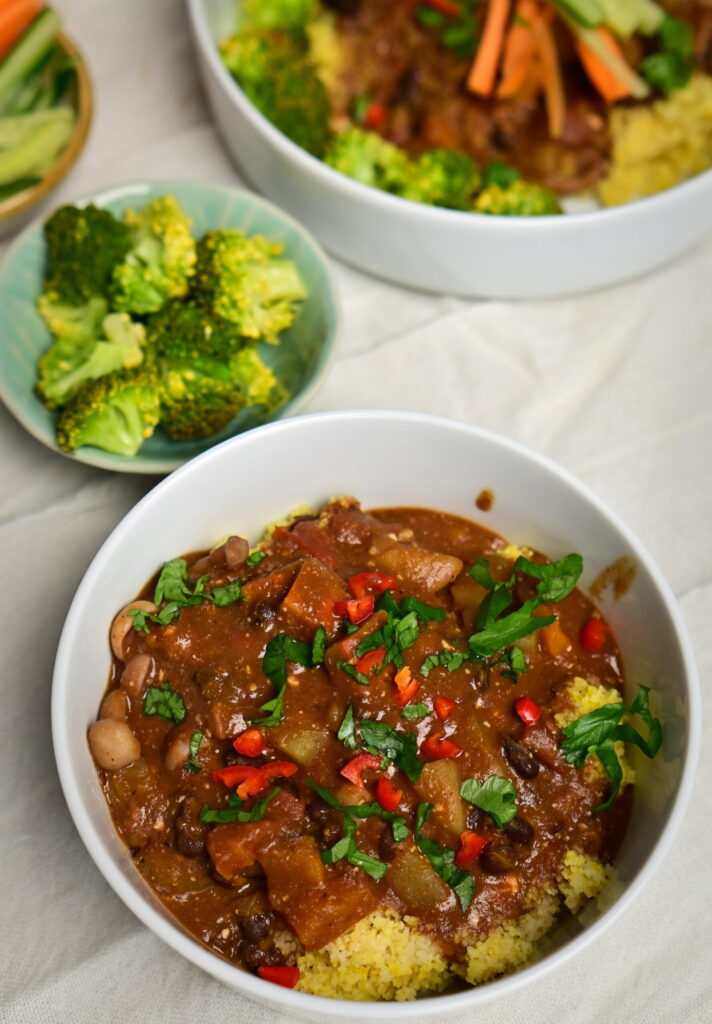 a bowl with black bean stew over couscous with chilli pepper and parsley
