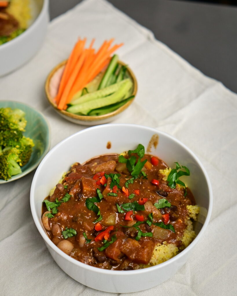 a bowl with black bean stew over couscous with chilli pepper and parsley