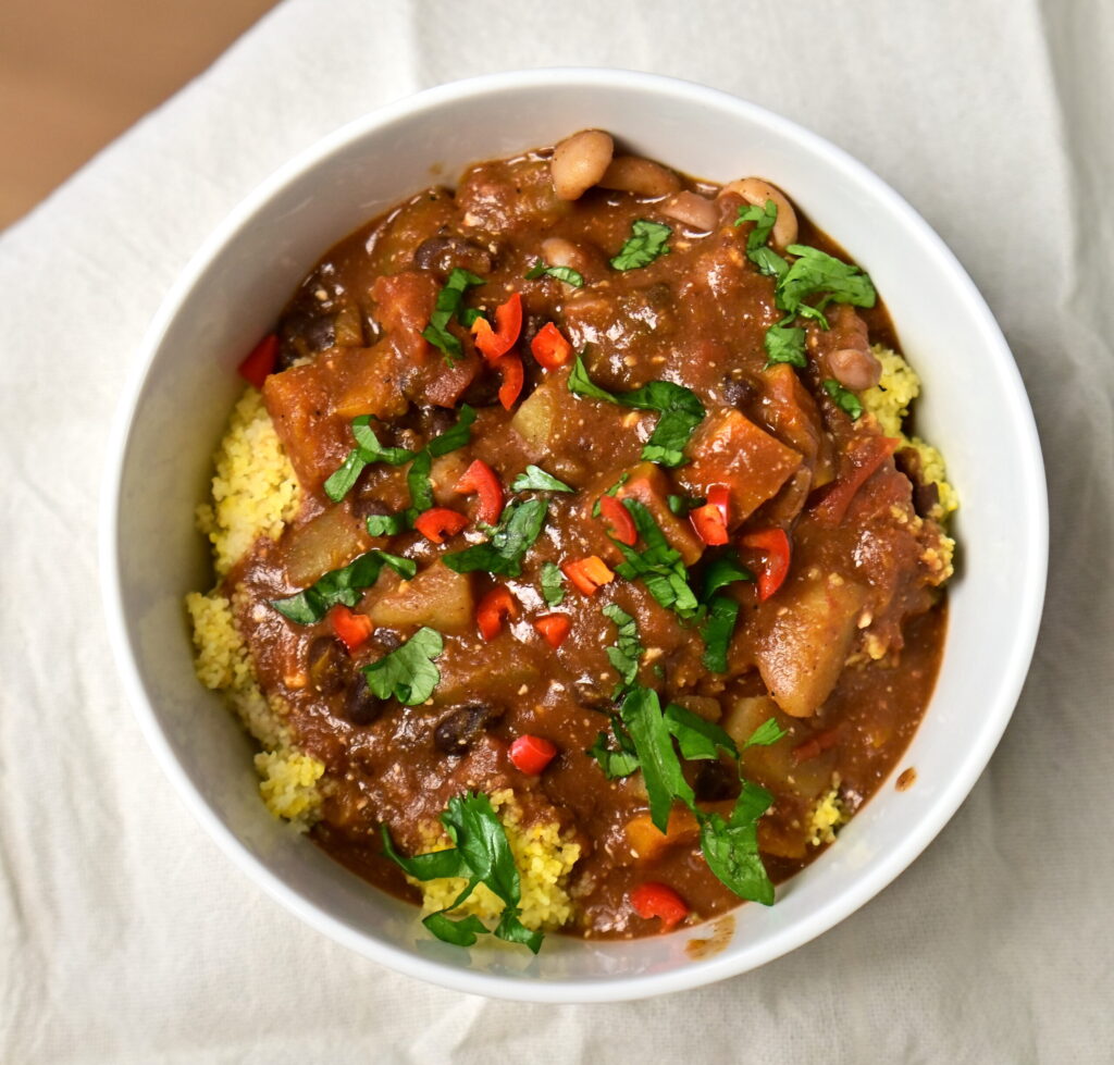 a bowl with black bean stew over couscous with chilli pepper and parsley