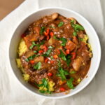 a bowl with black bean stew over couscous with chilli pepper and parsley
