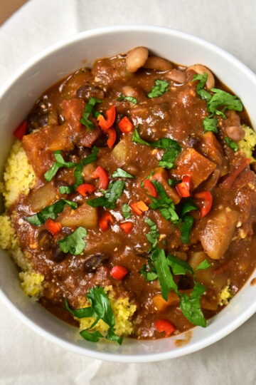 a bowl with black bean stew over couscous with chilli pepper and parsley
