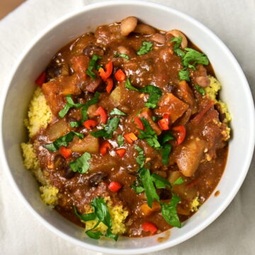 a bowl with black bean stew over couscous with chilli pepper and parsley