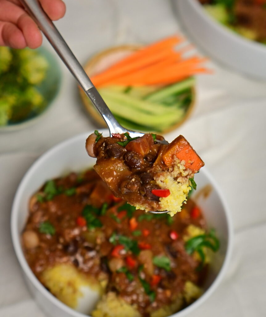 spoon with black bean stew with couscous over a bowl