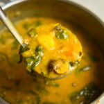 Lemony chickpea and vegetable soup with a ladle above a pot of soup.