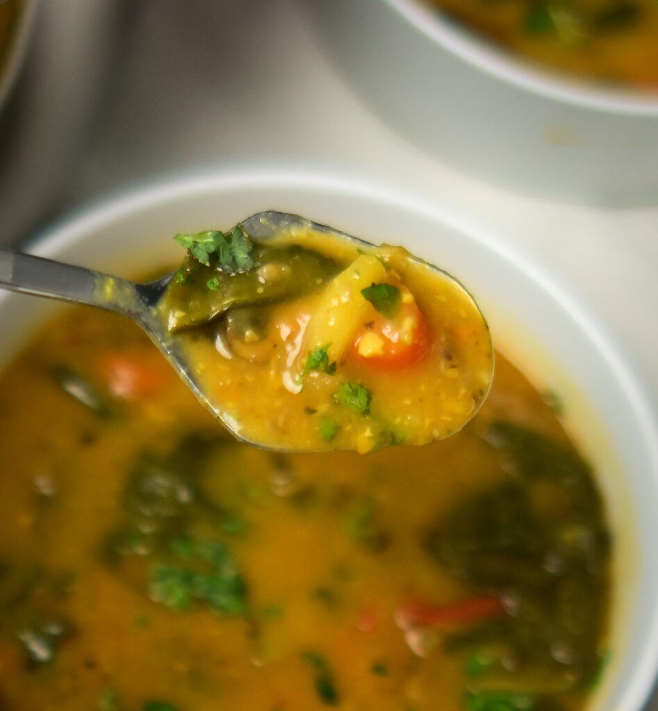 Lemony chickpea and vegetable soup with a spoon above a bowl of soup.