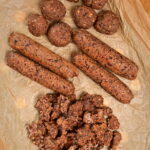 Seitan sausages, meatballs, and chorizo-style pieces arranged on brown parchment paper.