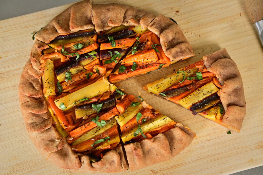 A colorful carrot galette on a wooden board.
