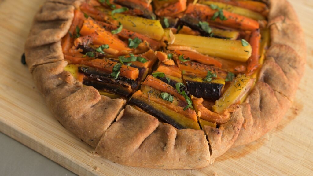 A colorful carrot galette on a wooden board.