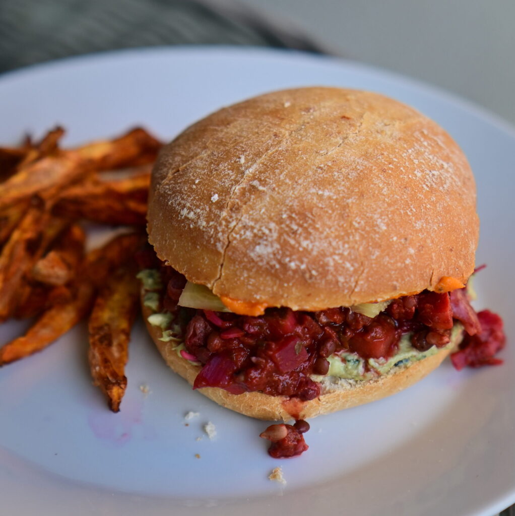 A vegan sloppy joe with Veggie-Packed Vegan Mince and sweet potato fries.